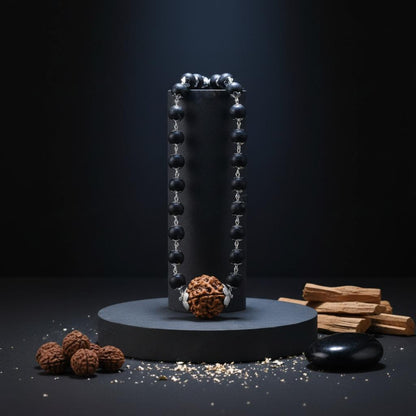 Karungali beaded object on a dark background with additional items like wood sticks and seeds.
